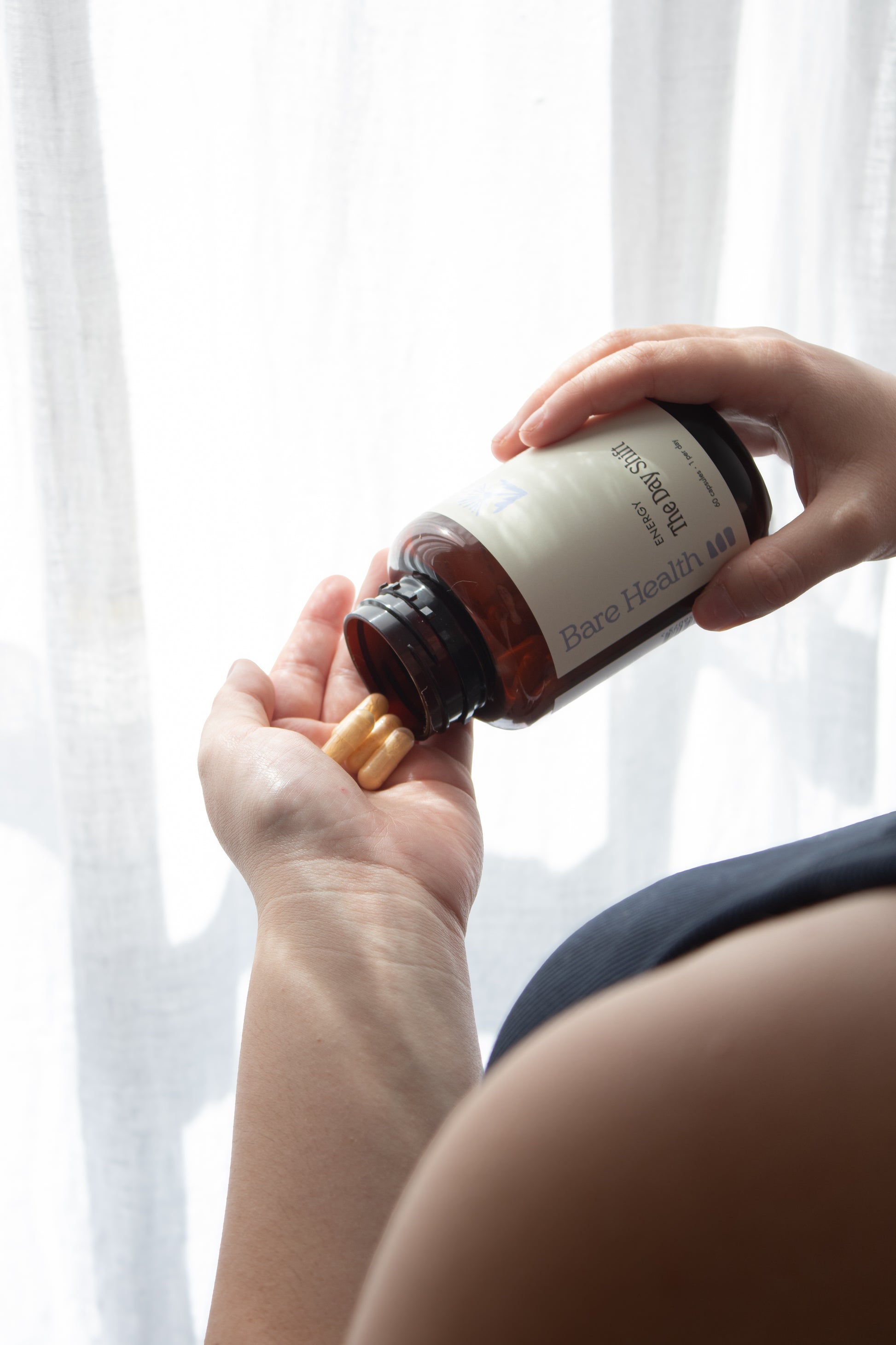 Person holding a bottle of supplements with a blurred background