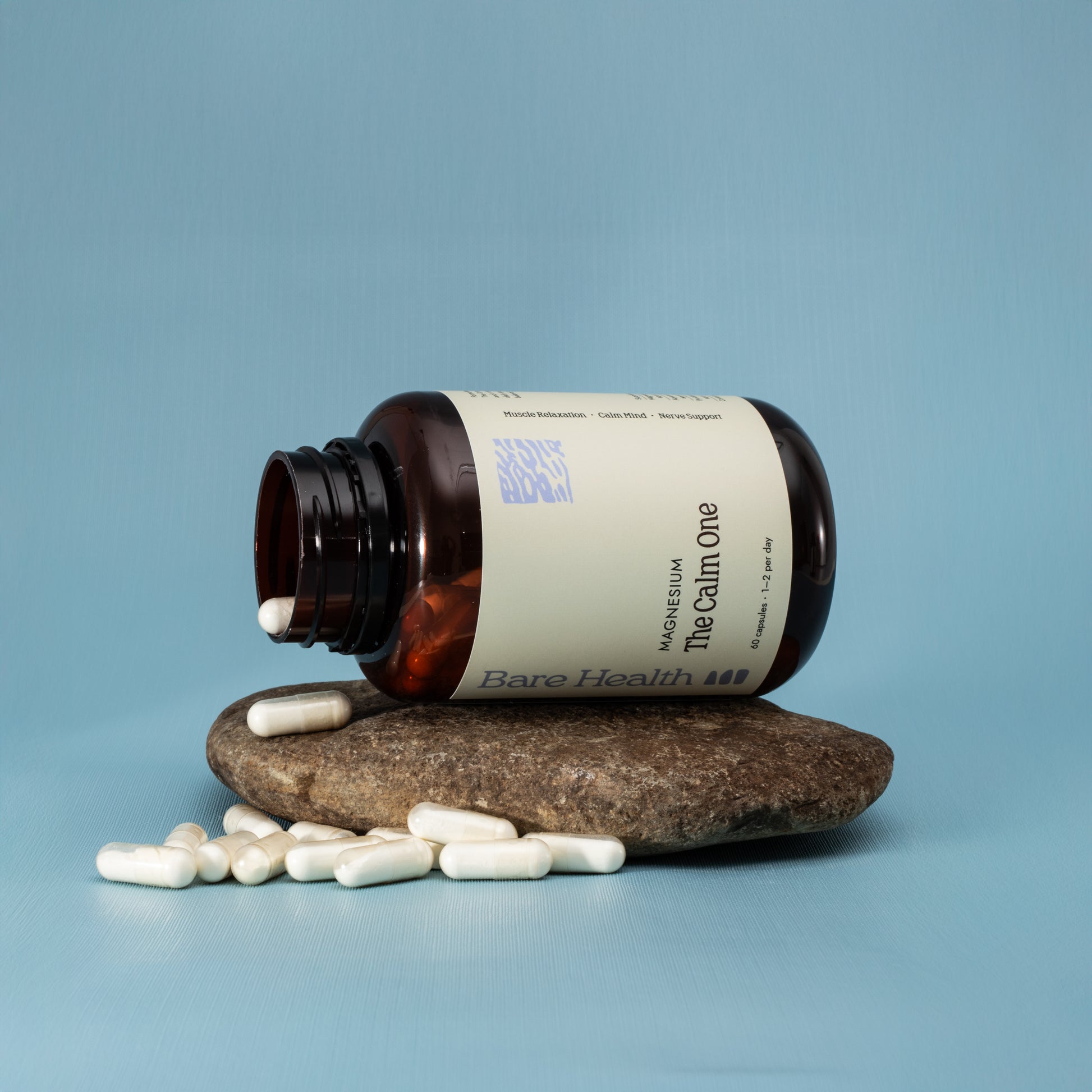 Bottle of 'The Calm One' by Bare Health with pills on a stone and blue background